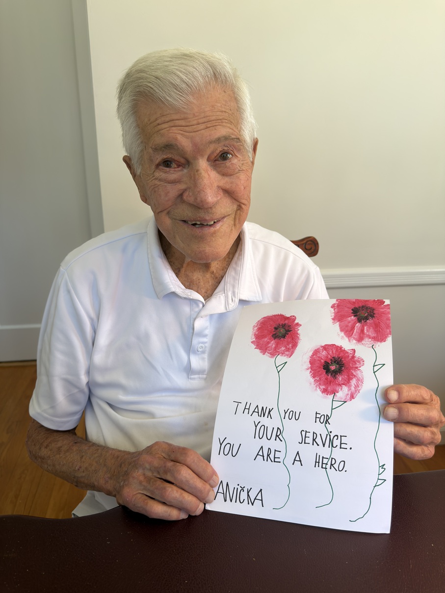 John Banham holding a thank-you letter and painting from Czech children.