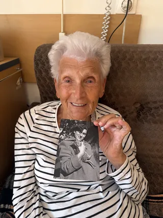 Doris Broulova holding a historical portrait photograph.