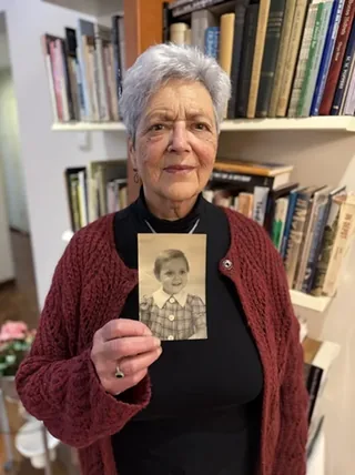 Esther Boas holding a photograph of herself as a young child.