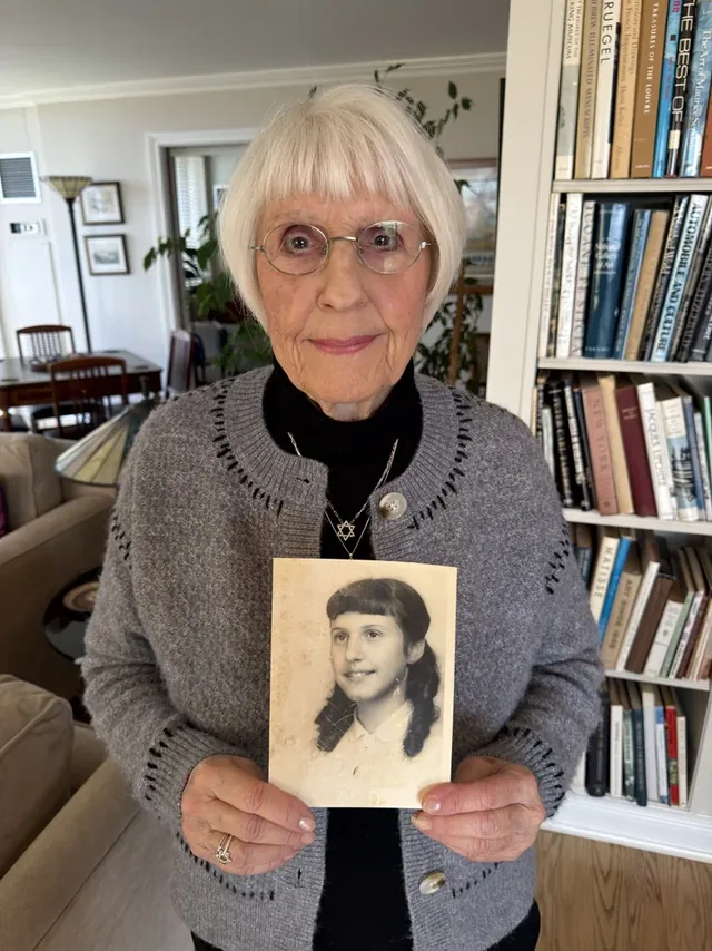 Eva Kessner holding a photograph of herself as a young girl.