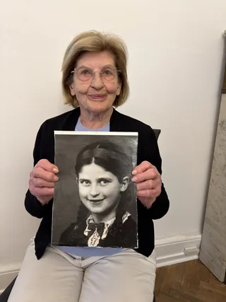 Eva Szepesi holding a photograph of herself as a young girl.