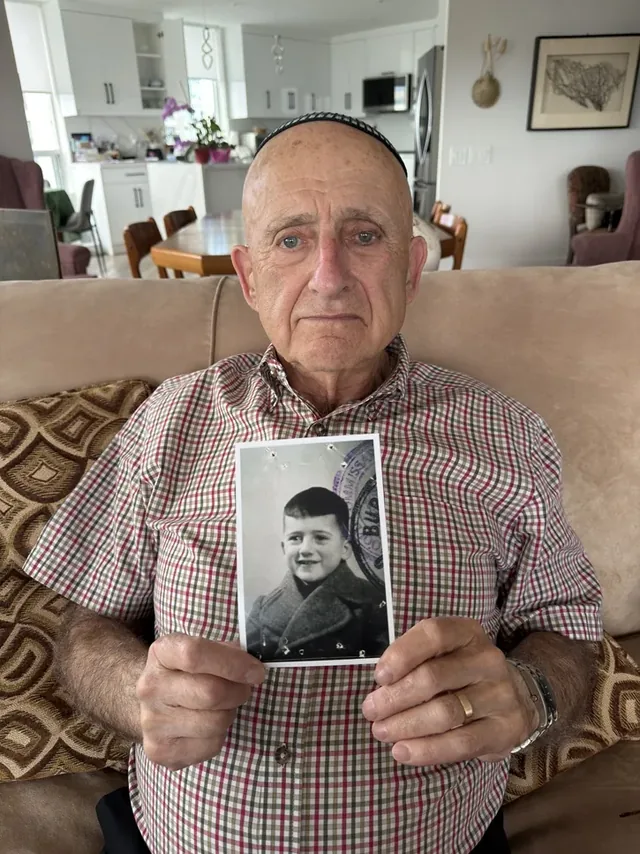 Gershon Willinger holding a photograph of himself as a child.