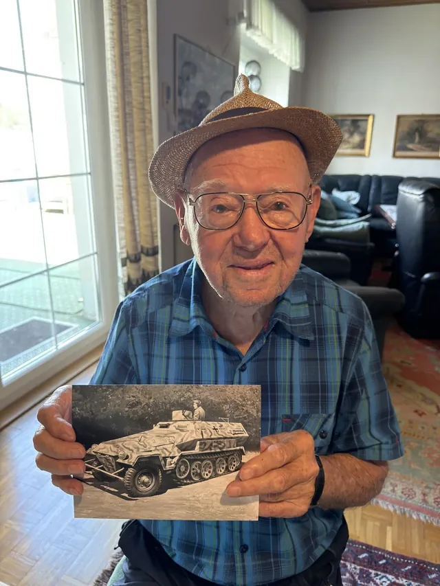 Hans Klingesberger holding a photograph of an armoured half-track.