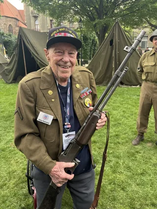 Harry Humason holding a Browning Automatic Rifle during a commemorative event.