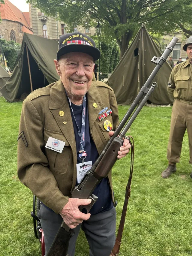 Harry Humason holding a Browning Automatic Rifle during a commemorative event.