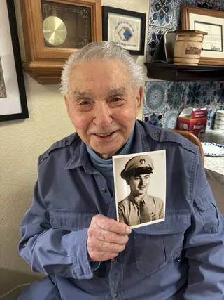 Harvey Drahos holding a photograph of himself in military uniform.