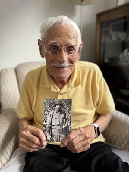 Jack Boeki holding a photograph of himself in military uniform.