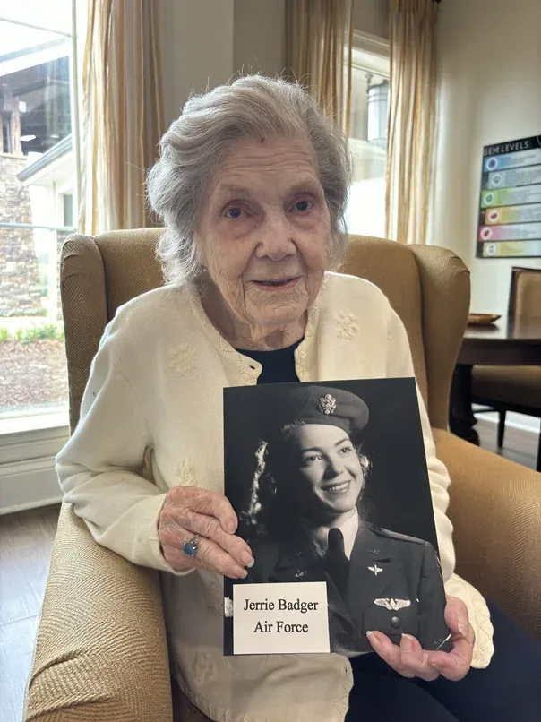 Jerrie Badger holding a photograph of herself in uniform.