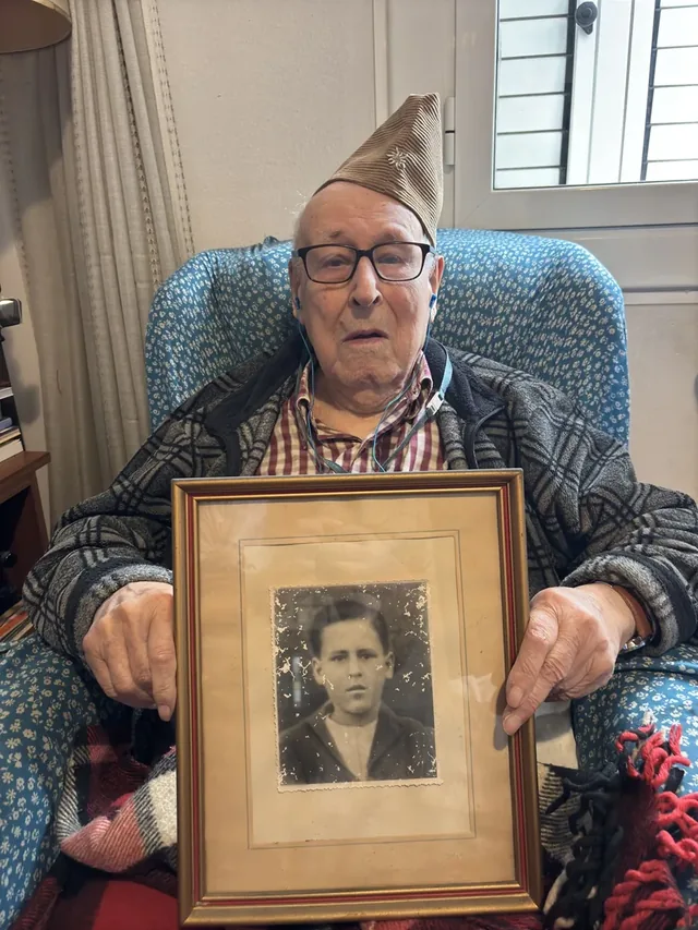 Joan Escudé i Farriol holding a framed portrait of himself as a young man.