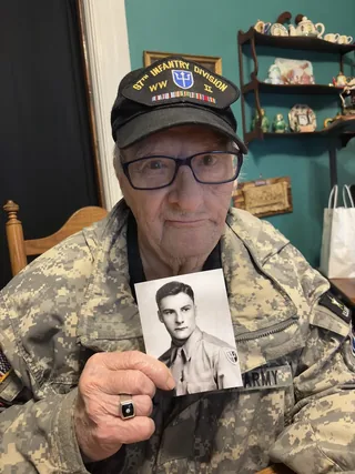 John Burke holding his wartime portrait.