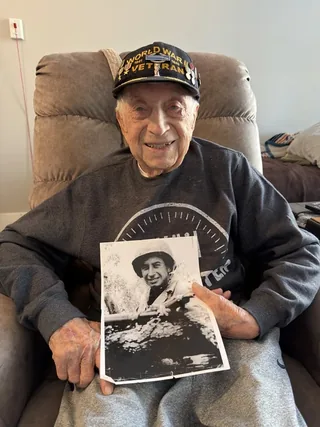Joseph Pietroforte holding a wartime photograph of himself.