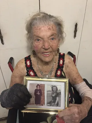 Lena Goren holding framed photographs from her younger years.