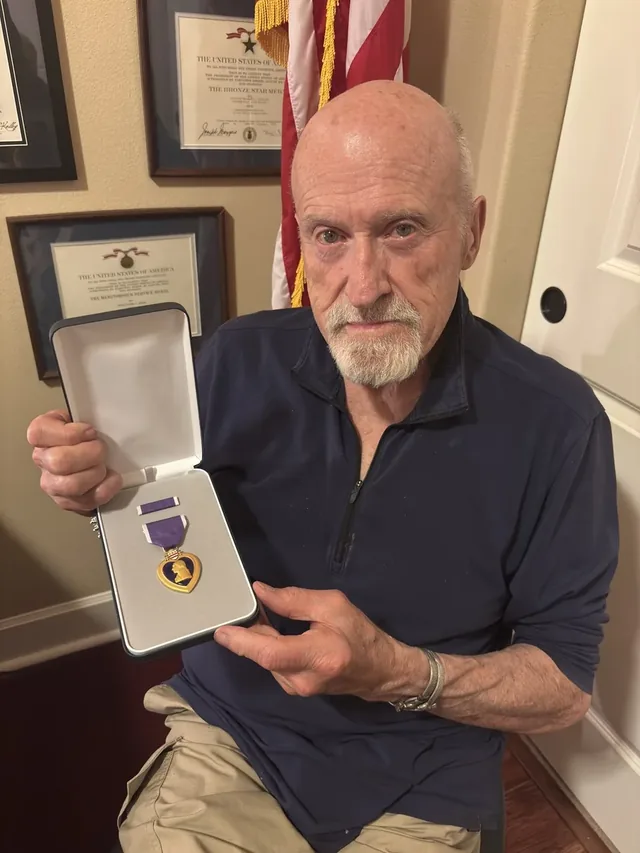 Michael Burton holding a case displaying his Purple Heart medal.