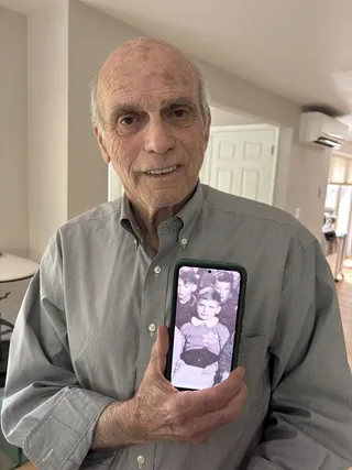 Peter Metzelaar holding a phone displaying a photograph of himself as a child.