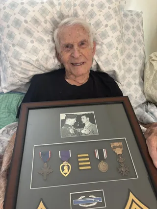Richard Thomas with a framed display of his military photograph and decorations.