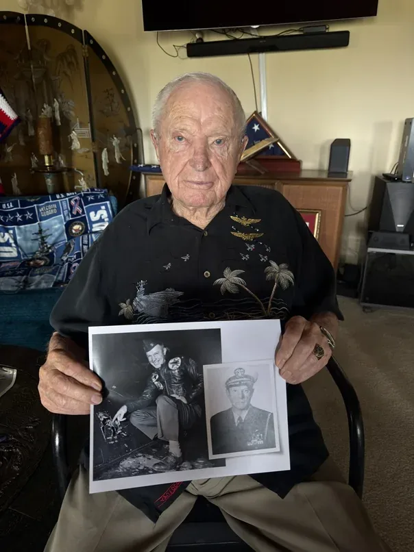 Royce Williams holding photographs from his naval aviation career.
